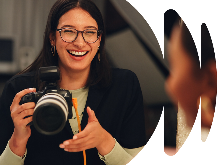 A photographer adjusting camera settings while looking through the viewfinder.